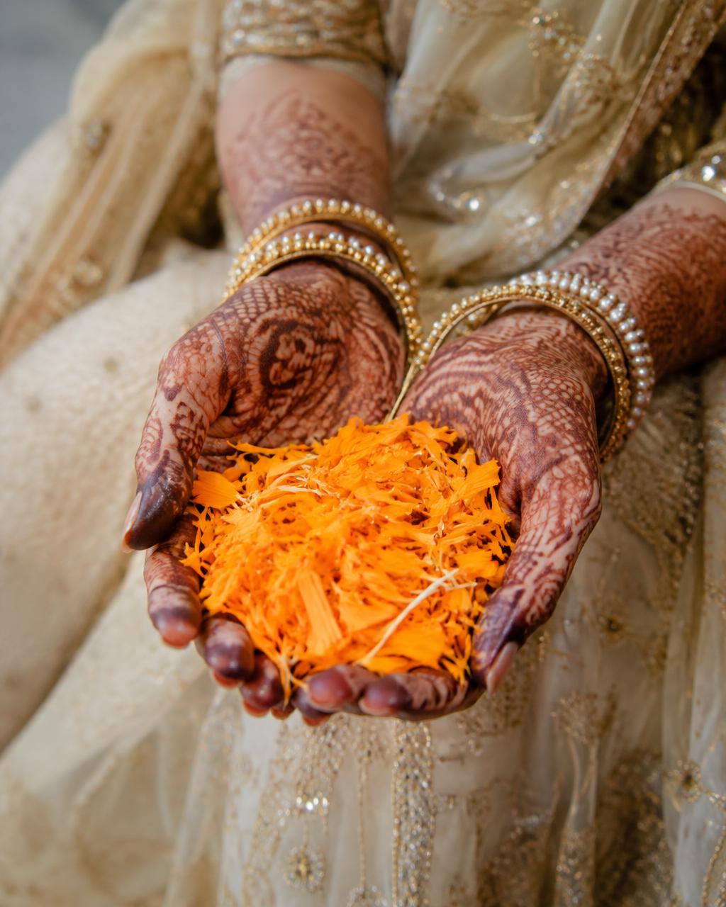 Hennaed hands holding marigold petals